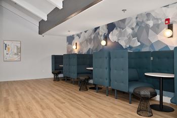 A room with blue couches and stools and a wall with a geometric design